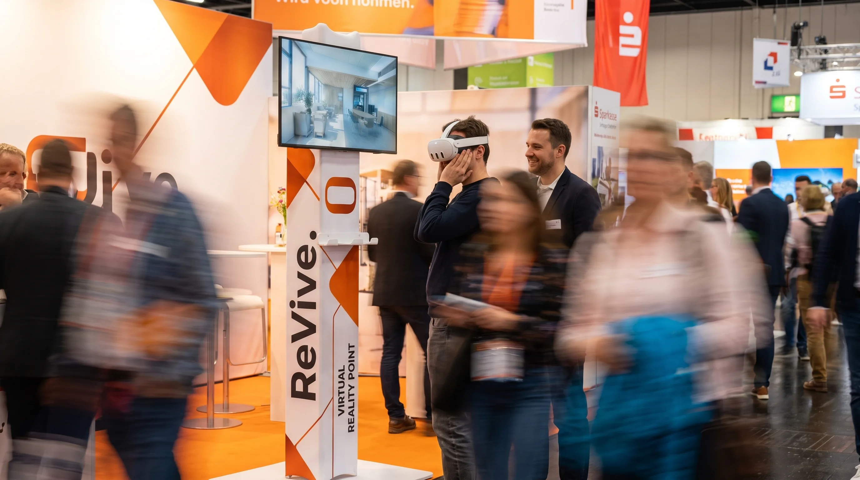 Messestand: ein Besucher mit VR-Brille steht mitten in der begehbaren Musterwohnung, auf dem Bildschirm der ReVive-Stele läuft seine Sicht mit, ein Berater schaut zu
